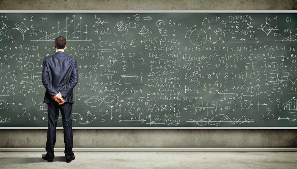 Business person standing against the blackboard with a lot of data written on it.jpeg